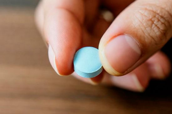 Рука держит синюю таблетку